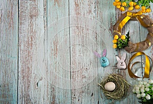 Blank for a wreath, a nest with an egg,  handmade Easter bunnies, flowers, ribbons and a bow on a wooden background.