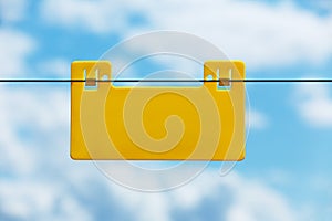 Blank yellow info plate hung on an electrical fence against blue sky