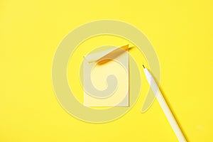 blank yellow paper note pad stick on vivid yellow background beside yellow pen