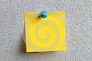 Blank Yellow Post-it Note with Blue Push Pin on Wall