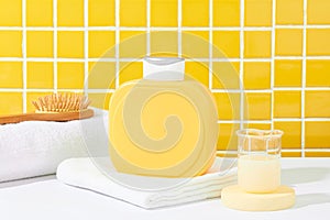 A blank yellow shower gel bottle rests on a white table against a checkered tile background. Elevate advertising with this perfect