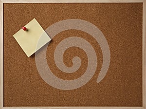 Blank yellow sticky note pinned on a cork bulletin board.