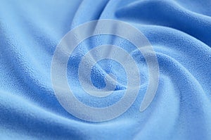 The blanket of furry blue fleece fabric. A background of light blue soft plush fleece material with a lot of relief folds