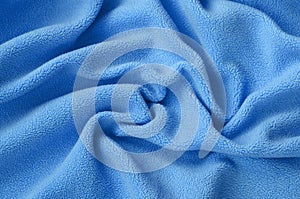 The blanket of furry blue fleece fabric. A background of light blue soft plush fleece material with a lot of relief folds