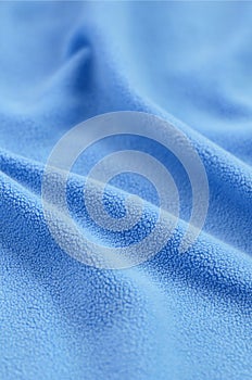 The blanket of furry blue fleece fabric. A background of light blue soft plush fleece material with a lot of relief folds