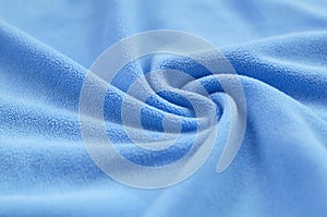 The blanket of furry blue fleece fabric. A background of light blue soft plush fleece material with a lot of relief folds