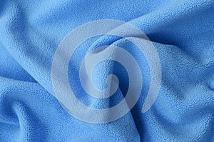 The blanket of furry blue fleece fabric. A background of light blue soft plush fleece material with a lot of relief folds