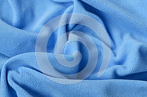 The blanket of furry blue fleece fabric. A background of light blue soft plush fleece material with a lot of relief folds