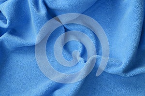 The blanket of furry blue fleece fabric. A background of light blue soft plush fleece material with a lot of relief folds