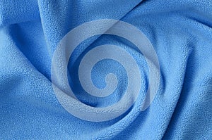 The blanket of furry blue fleece fabric. A background of light blue soft plush fleece material with a lot of relief folds