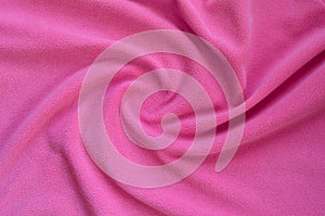 The blanket of furry pink fleece fabric. A background of light pink soft plush fleece material with a lot of relief fold