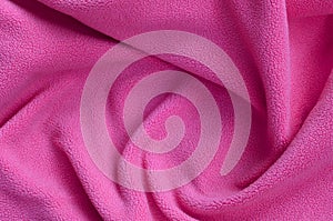 The blanket of furry pink fleece fabric. A background of light pink soft plush fleece material with a lot of relief folds