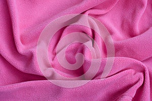 The blanket of furry pink fleece fabric. A background of light pink soft plush fleece material with a lot of relief folds