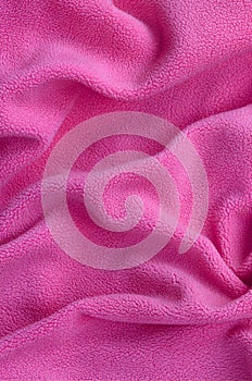 The blanket of furry pink fleece fabric. A background of light pink soft plush fleece material with a lot of relief folds photo