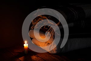 A blanket and a pillow folded in a stack on a background of fire candles in a dark bedroom