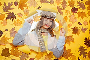 This blanket scarf has a lovely soft feel. Fashion girl look through torn paper with autumn leaves. Cute woman wear