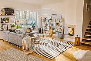 Blanket thrown on grey corner sofa in white living room interior