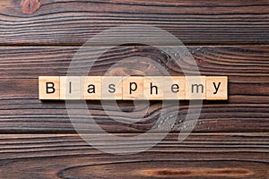 BLASPHEMY word written on wood block. BLASPHEMY text on cement table for your desing, concept