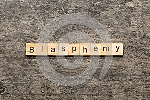 BLASPHEMY word written on wood block. BLASPHEMY text on cement table for your desing, concept