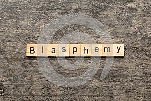 BLASPHEMY word written on wood block. BLASPHEMY text on cement table for your desing, concept photo