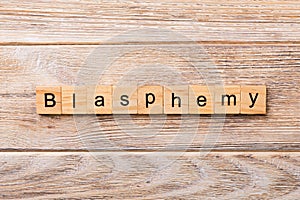 BLASPHEMY word written on wood block. BLASPHEMY text on wooden table for your desing, concept