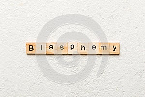 BLASPHEMY word written on wood block. BLASPHEMY text on cement table for your desing, concept photo