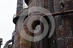 Blast furnaces and heavy metal architecture of an abandoned steel mill complex against a gray sky in winter