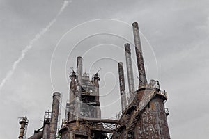 Blast furnaces and smokestacks of a steel mill silhouetted against a gray sky