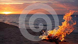 Blazing campfire on beach, summer evening. Bonfire in nature as background. Burning wood on white sand shore at sunset.