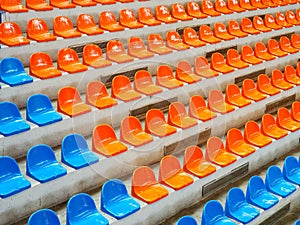 Bleachers, empty seats in the stands of the arena or auditorium. Rows of blue and orange stadium seats without