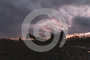 A bleak, moody, winter edit of a hooded figure standing next to quarry machinery, looking out to sunset on a winters evening