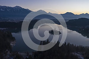 Bled Lake and Illuminated Marijinega Vnebovzetja Church and Blejski Castle in Morning Twilight. Blue Hour. Hills and