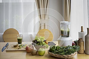 Blended with assorted organic vegetables and fruits on wooden table in kitchen.