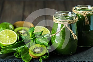 Blended green smoothie with ingredients on the stone board, wooden table