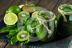 Blended green smoothie with ingredients on the stone board, wooden table