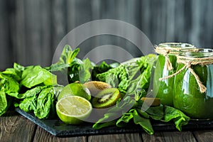 Blended green smoothie with ingredients on the stone board, wooden table