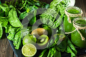 Blended green smoothie with ingredients on the stone board, wooden table