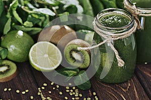 Blended green smoothie with ingredients on the stone board, wooden table