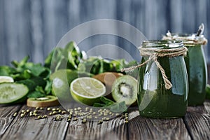 Blended green smoothie with ingredients on the stone board, wooden table