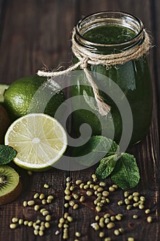 Blended green smoothie with ingredients on the stone board, wooden table