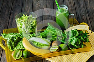 Blended green smoothie with ingredients on wooden table selective focus.