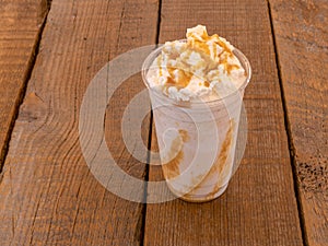 Blended Iced coffee caramel frappe in a plastic cup with whipping cream