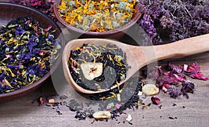 Blended tea with flower petals and dried fruit in a wooden spoon. close up