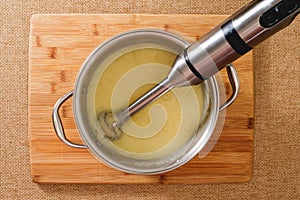 Blender in a cooking pan, flat lay. Creamy pureed celery soup recipe