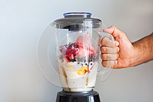 A blender filled with fresh whole fruits for making a smoothie or juice. Healthy eating concept