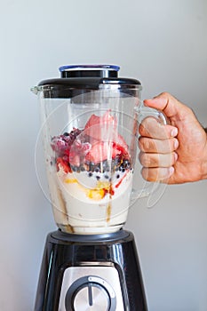 A blender filled with fresh whole fruits for making a smoothie or juice. Healthy eating concept