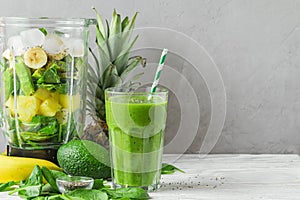 Blender with fresh ingredients to making healthy detox smoothie with glass of green prepared drink with a straw