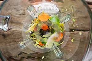Blender in the process of grinding vegetables on a wooden table, top view.Healthy and correct nutrition