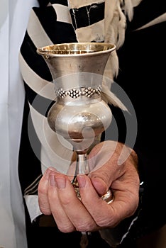 Blessing over a large, silver cup of wine at a Jewish wedding