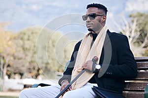 Blind black man, park bench and outdoor with sunglasses, walking stick or relax by trees, peace or thinking. African guy